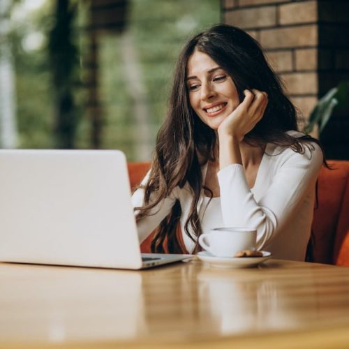 Young beautiful business woman working on cimputer in a cafe